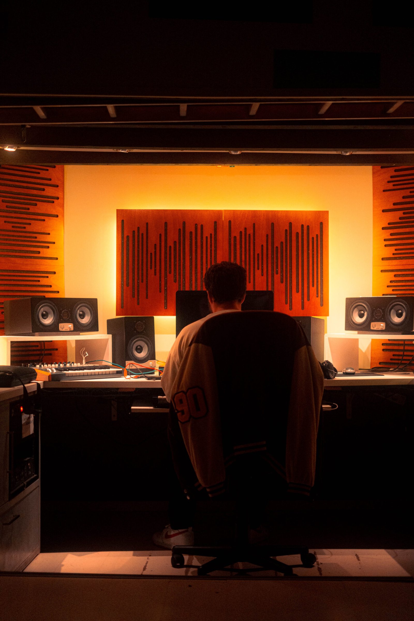 Heeron trabajando de espaldas en el estudio, frente a los monitores y los paneles acústicos